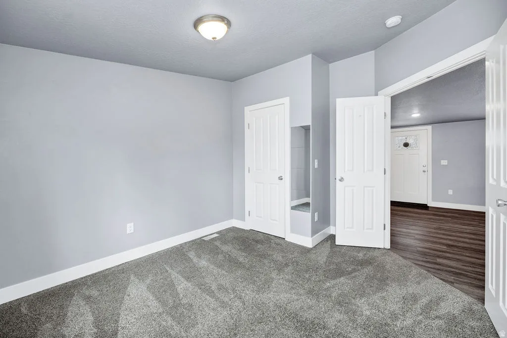 Unfurnished bedroom featuring dark colored carpet and a textured ceiling