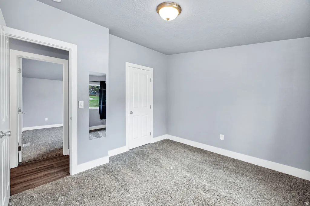 Unfurnished bedroom featuring carpet flooring, a textured ceiling, and a closet