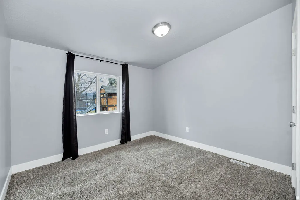 Empty room featuring baseboards and light carpet