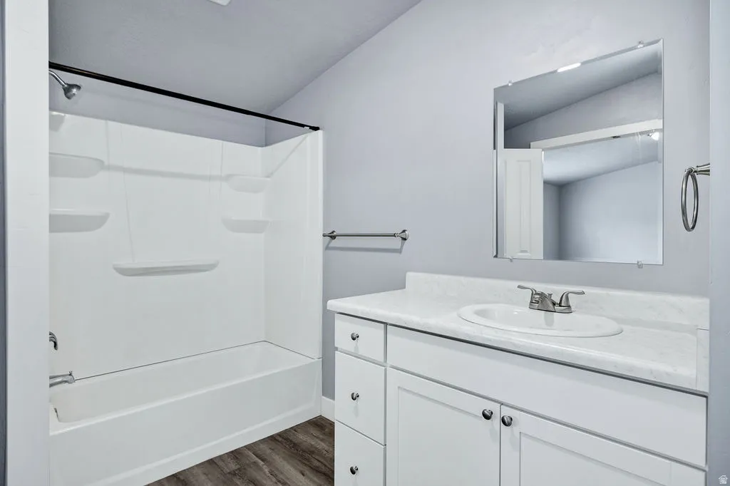 Bathroom with vanity, dark wood finished floors, bathtub / shower combination, and lofted ceiling