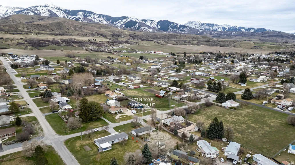 Aerial view of property and surrounding area featuring nearby suburban area and a mountain backdrop
