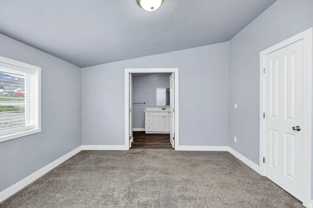 Unfurnished bedroom featuring ensuite bathroom and carpet flooring