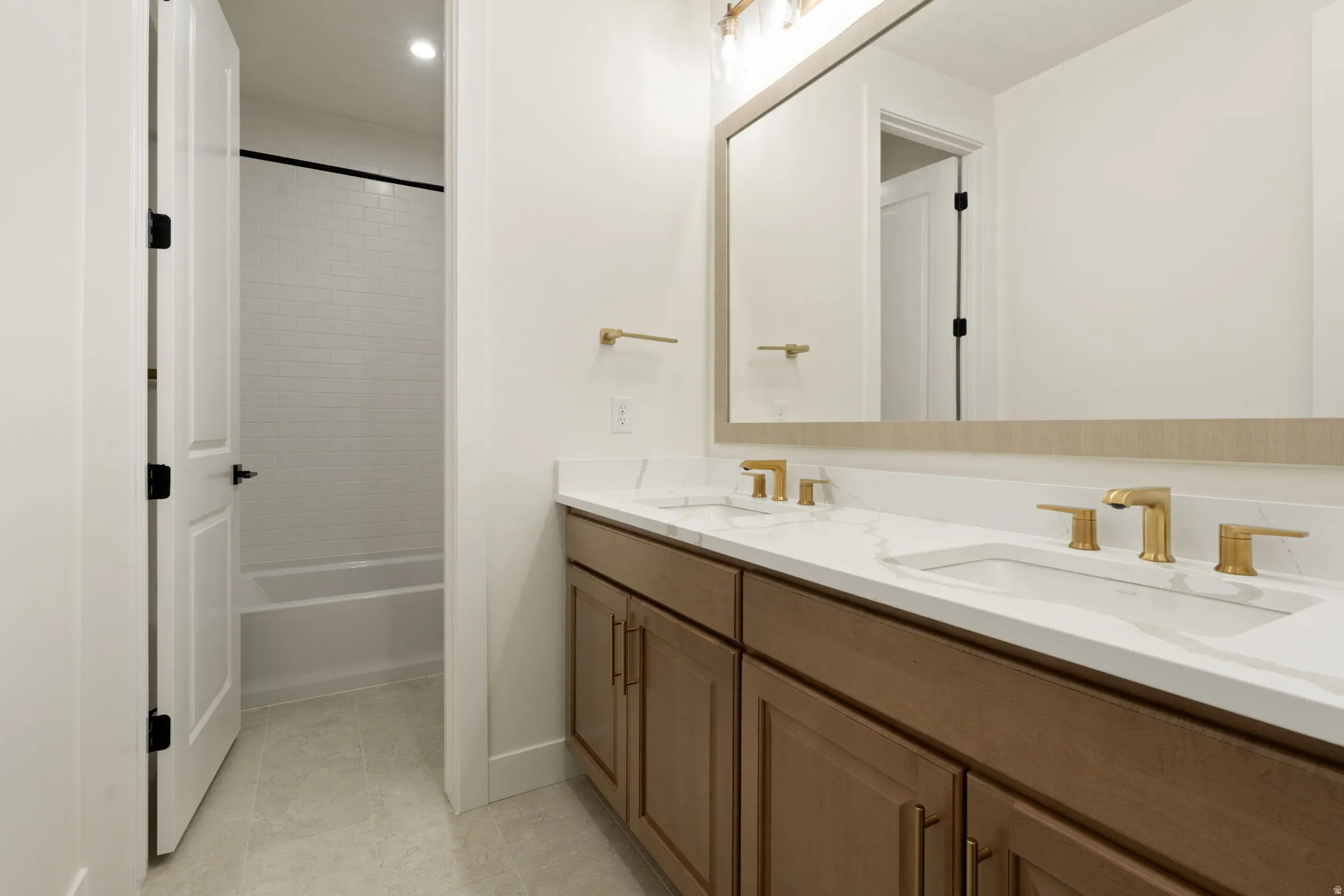 Bathroom featuring double vanity, bathing tub / shower combination, light tile patterned flooring, and recessed lighting