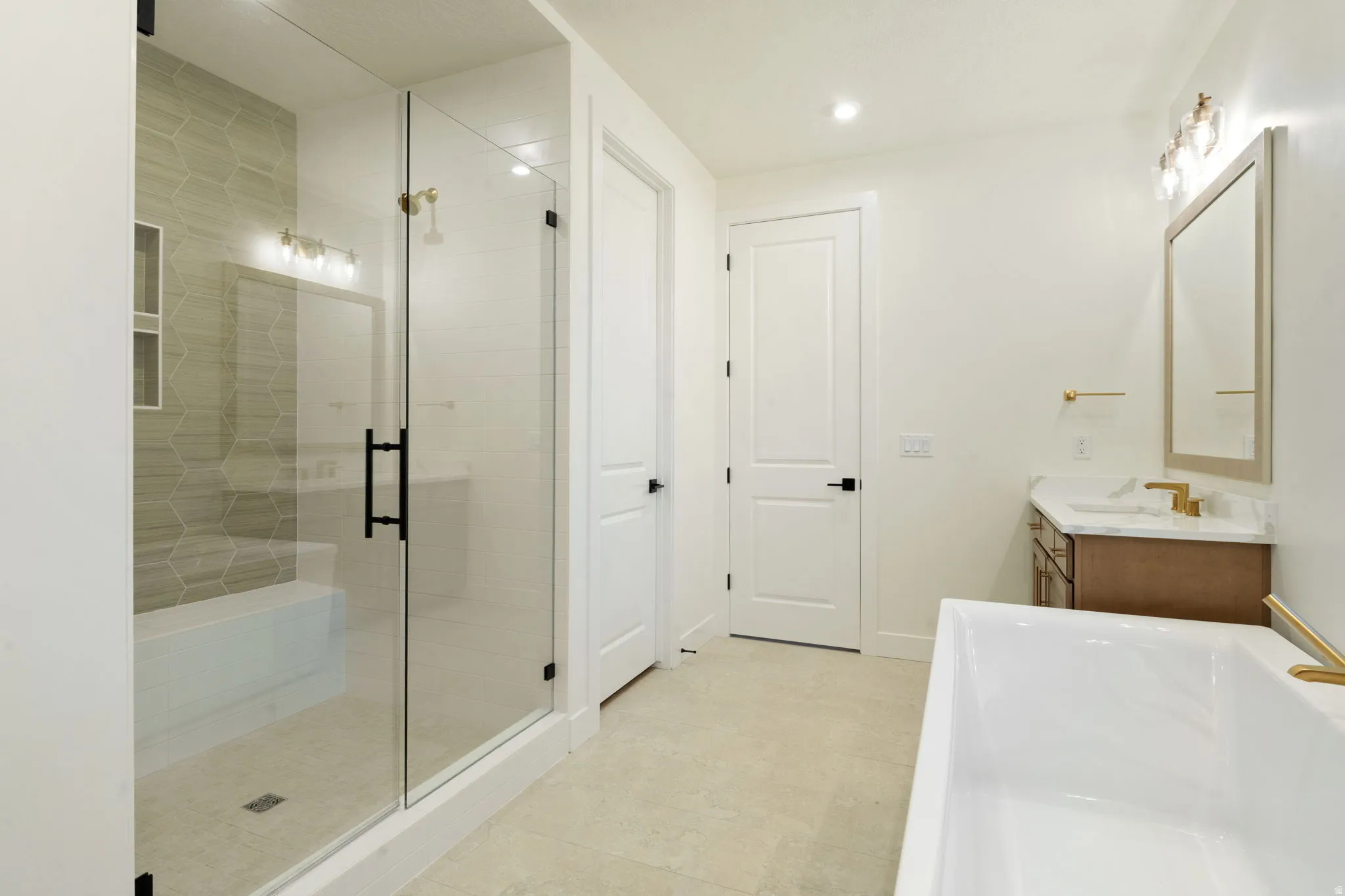 Bathroom with a freestanding bath, vanity, a stall shower, and recessed lighting