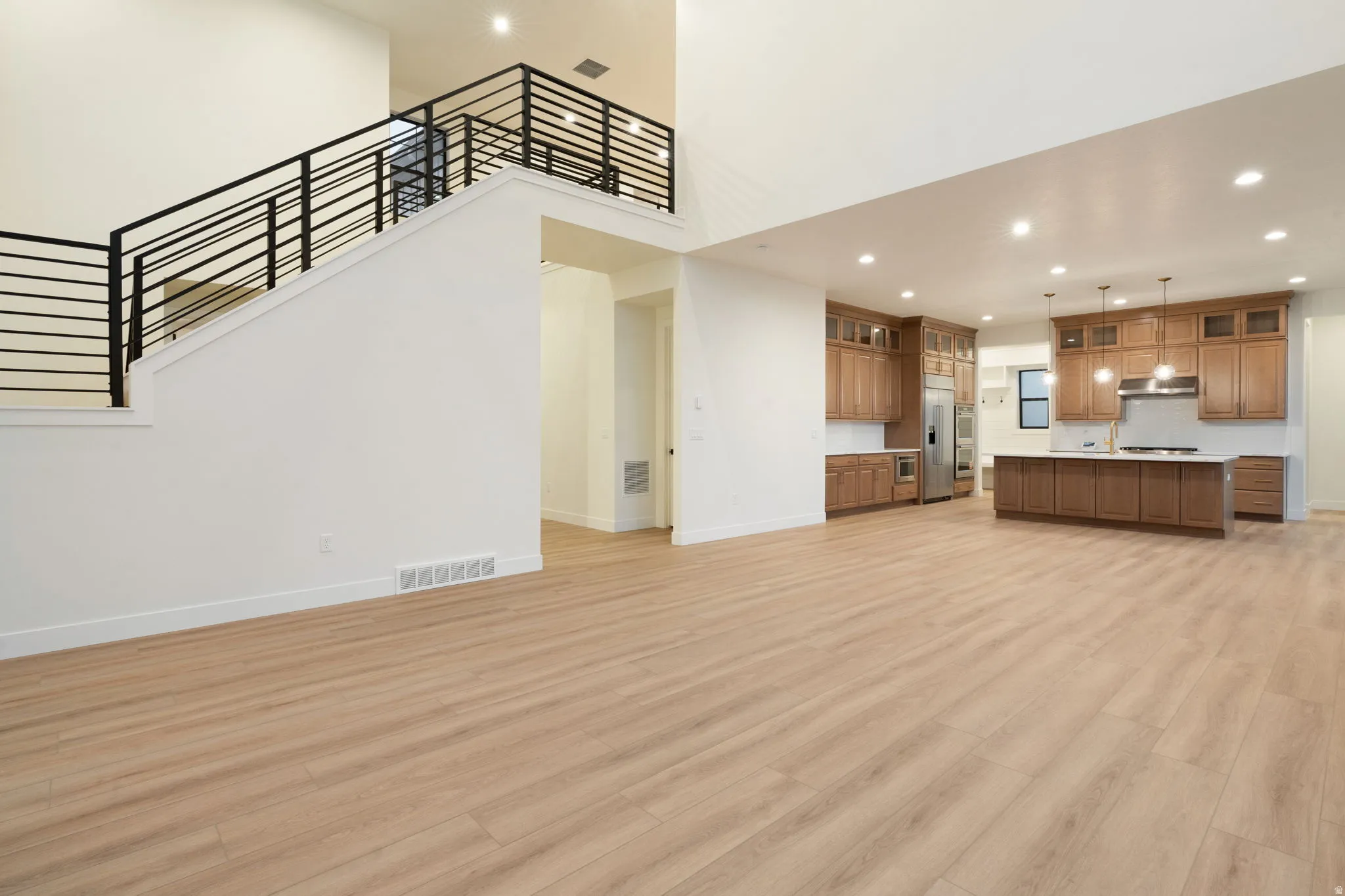 Unfurnished living room featuring recessed lighting, light wood-type flooring, and a high ceiling