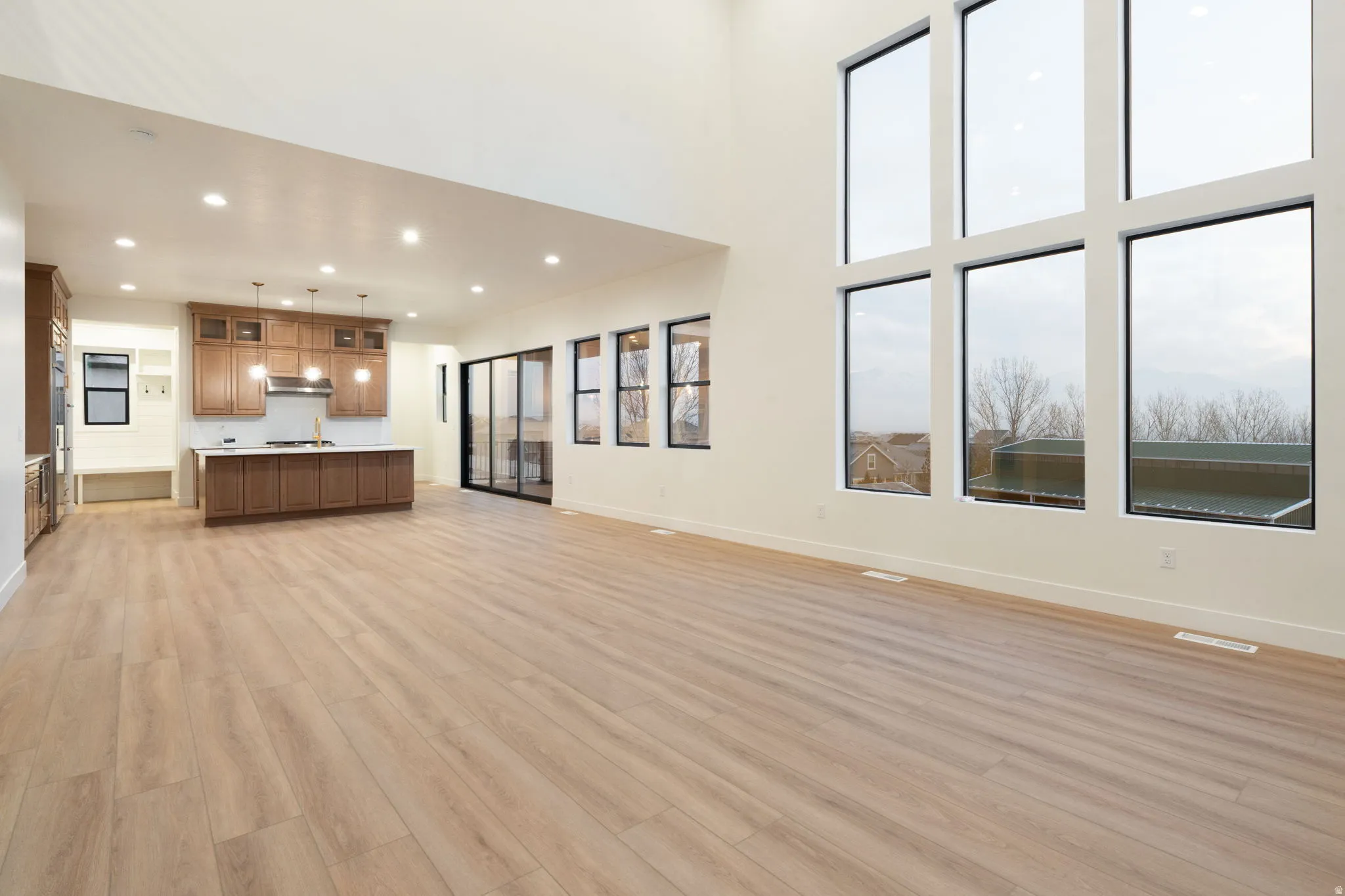 Unfurnished living room featuring light wood-type flooring, recessed lighting, and a high ceiling