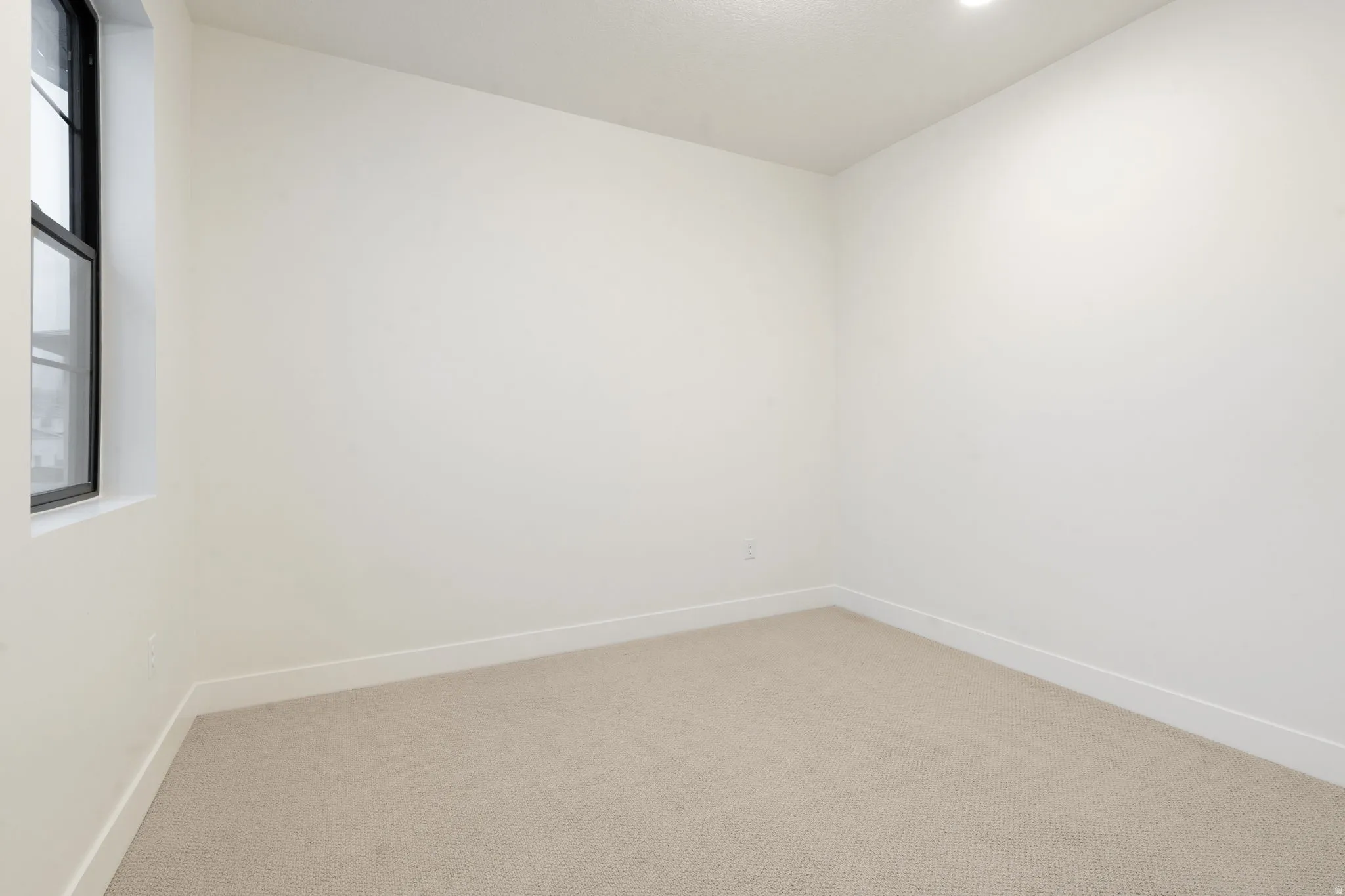 Carpeted spare room featuring baseboards