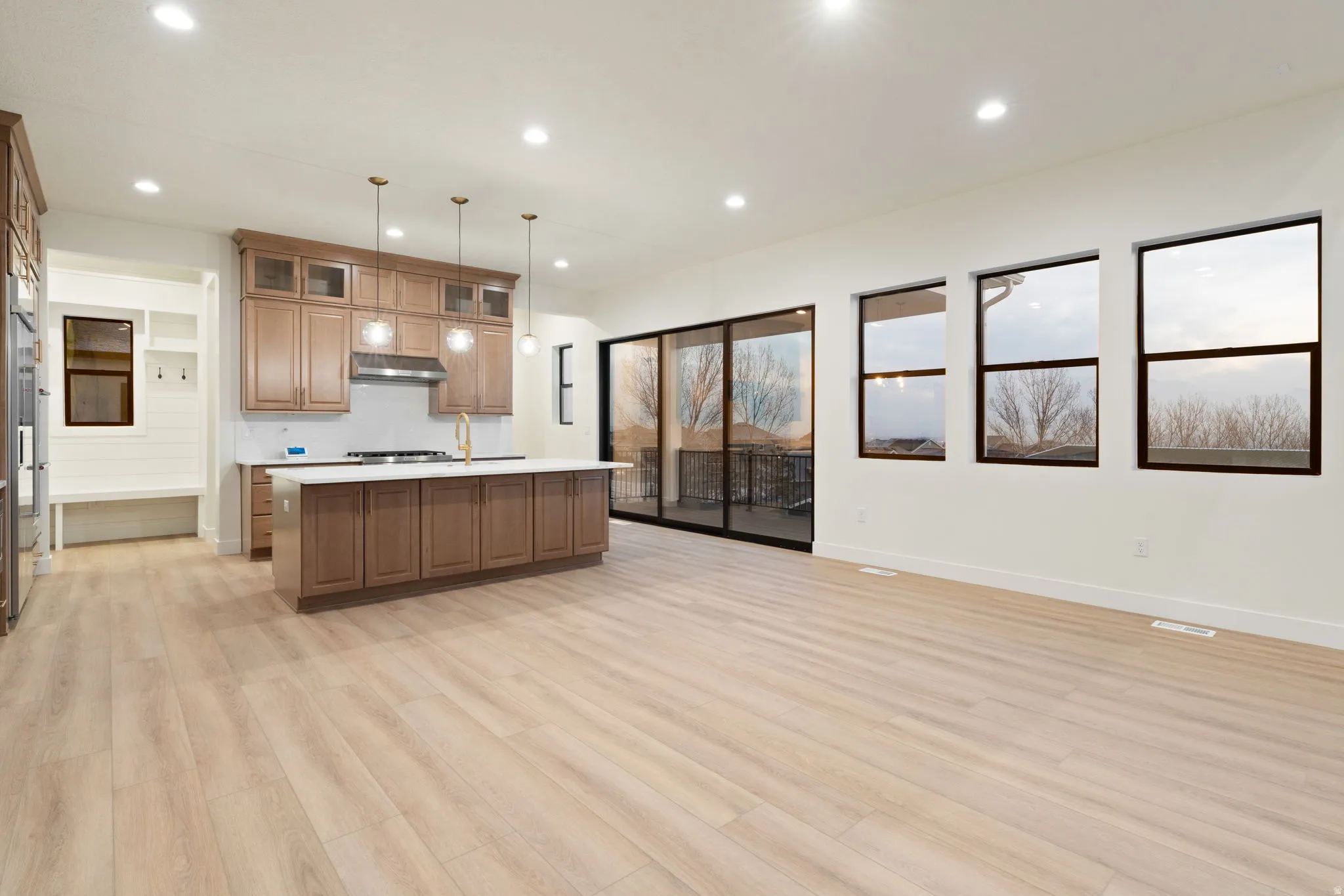 Kitchen featuring a kitchen island with sink, open floor plan, light countertops, wood finish cabinets, and light wood-type flooring