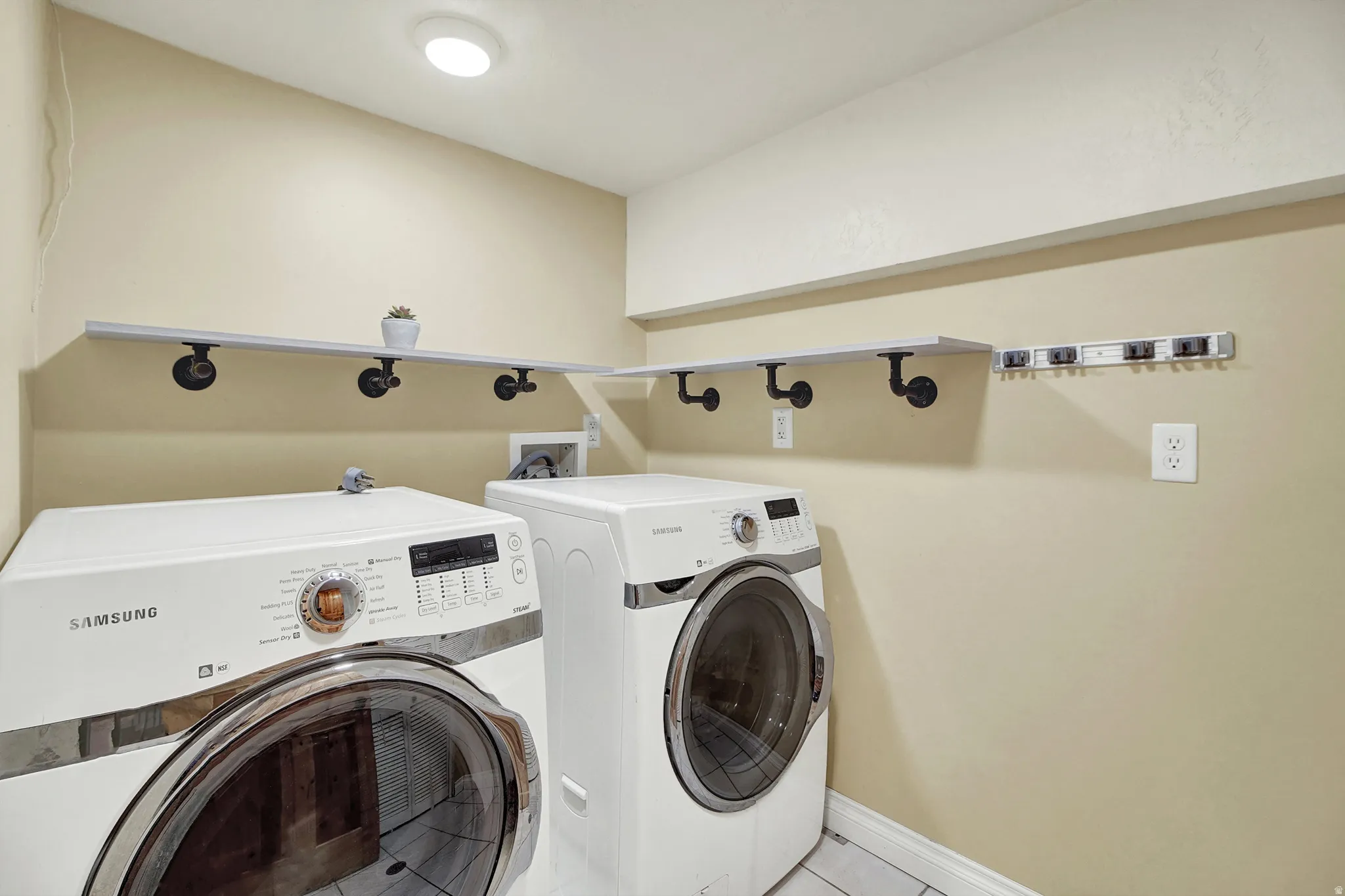 Laundry area featuring washer and clothes dryer and light tile patterned floors