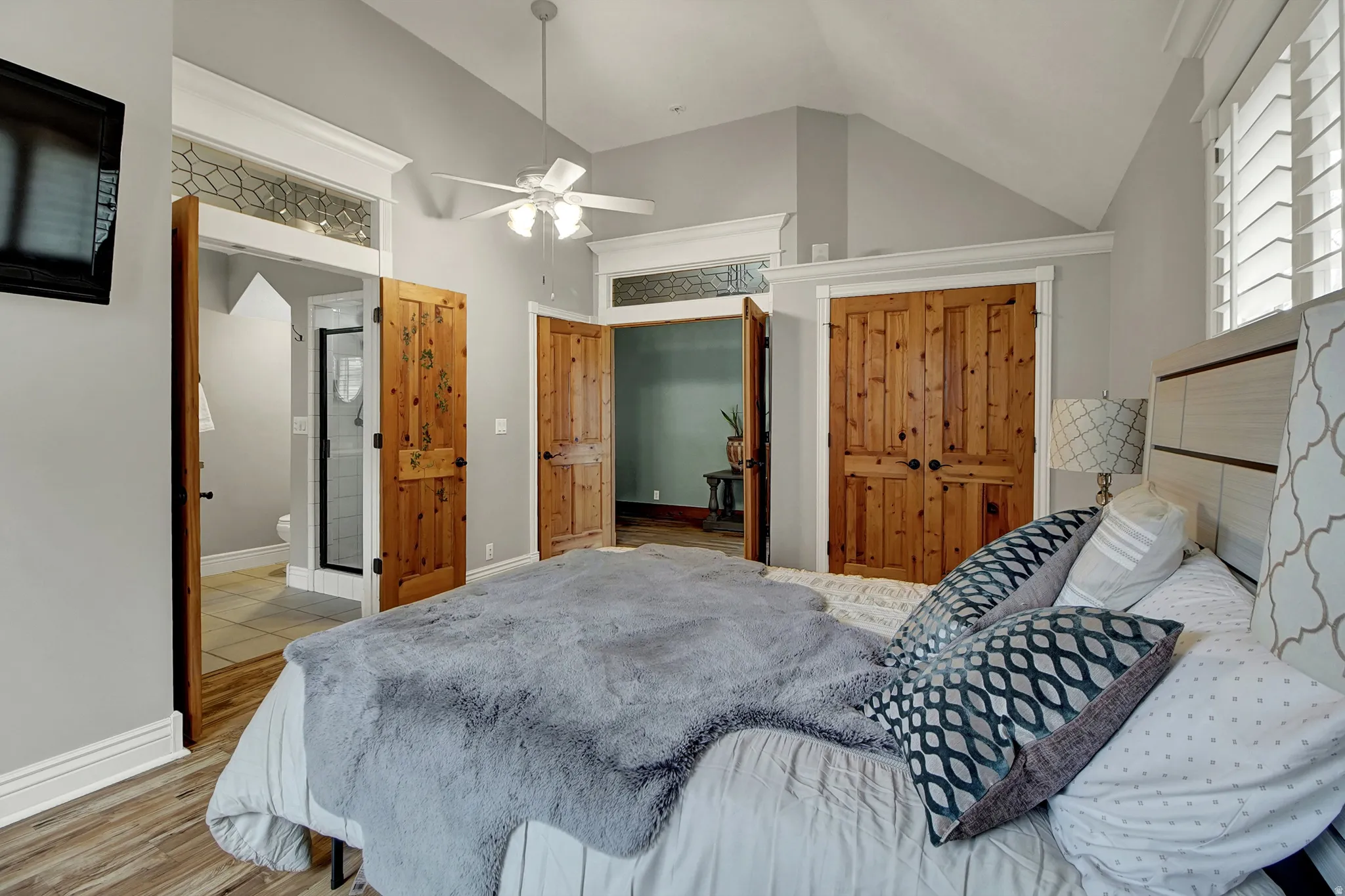 Bedroom with light wood-style floors, vaulted ceiling, a closet, ceiling fan, and connected bathroom