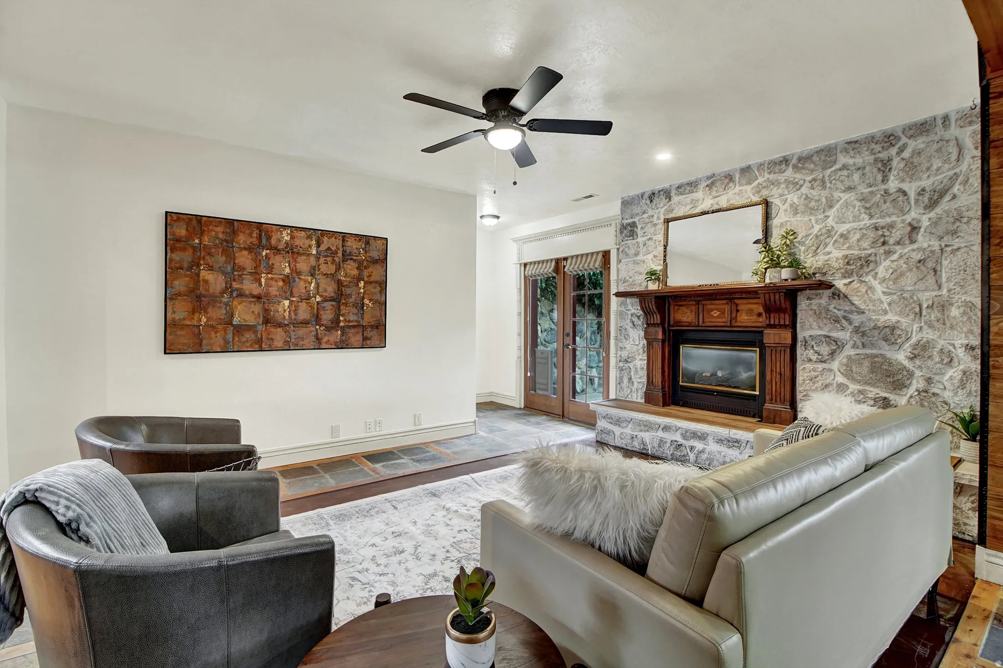 Living room featuring a large fireplace, a ceiling fan, and wood finished floors