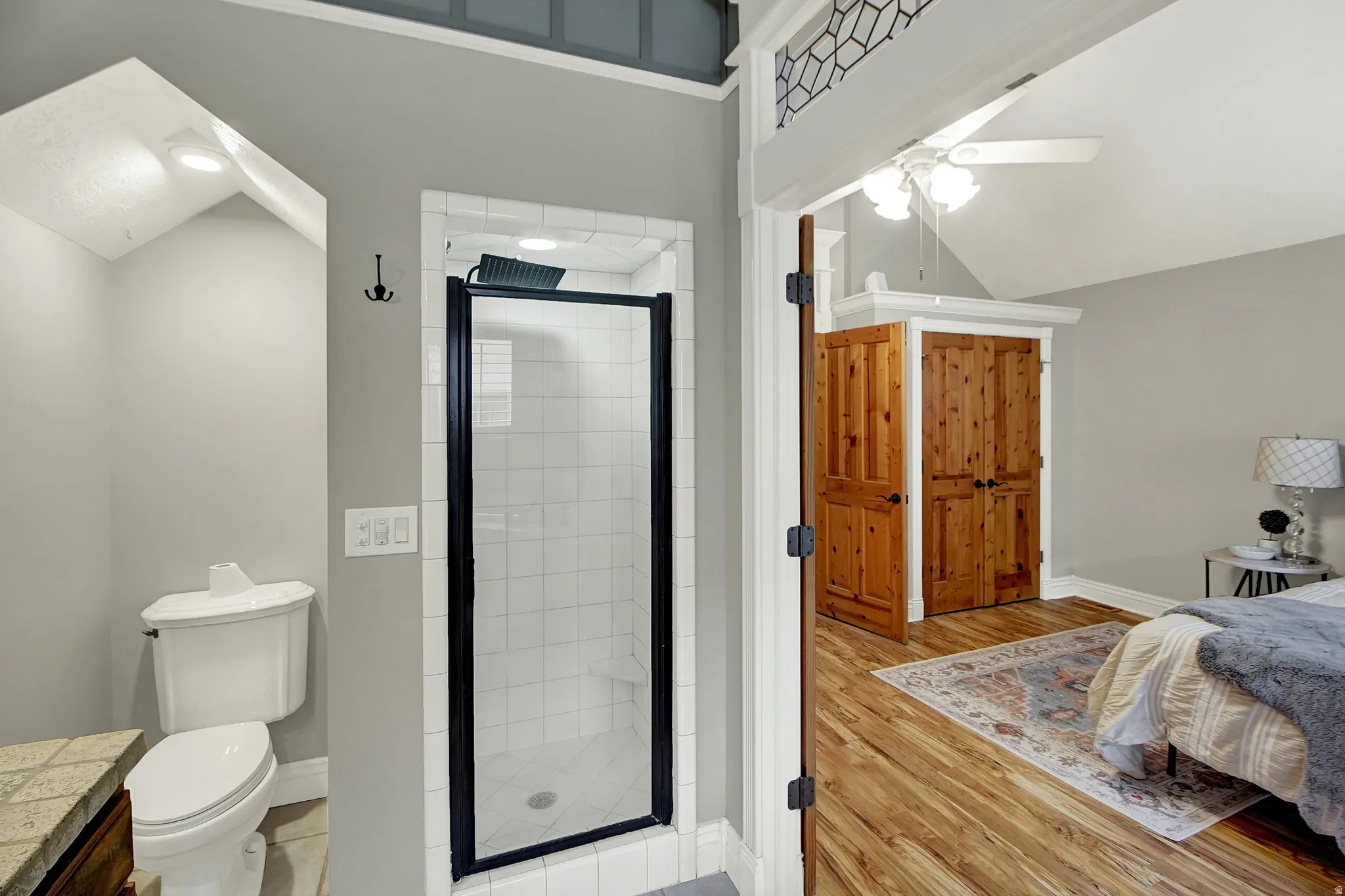 Bathroom featuring a stall shower, light wood finished floors, vanity, a ceiling fan, and vaulted ceiling