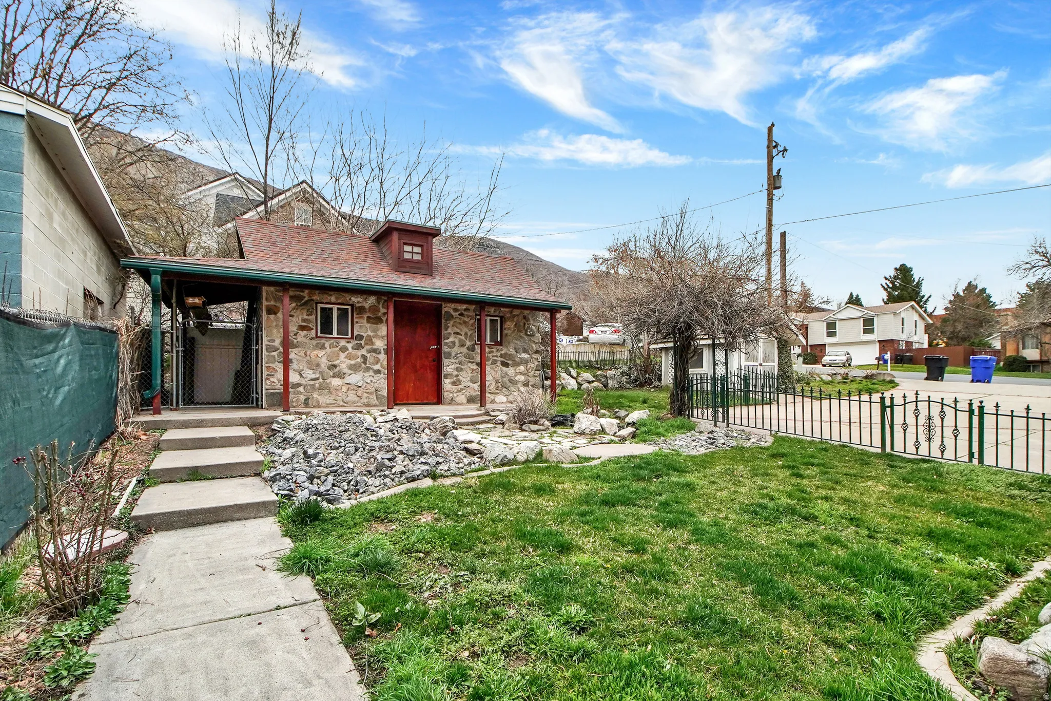 View of front of home featuring covered porch, stone siding, and a residential view