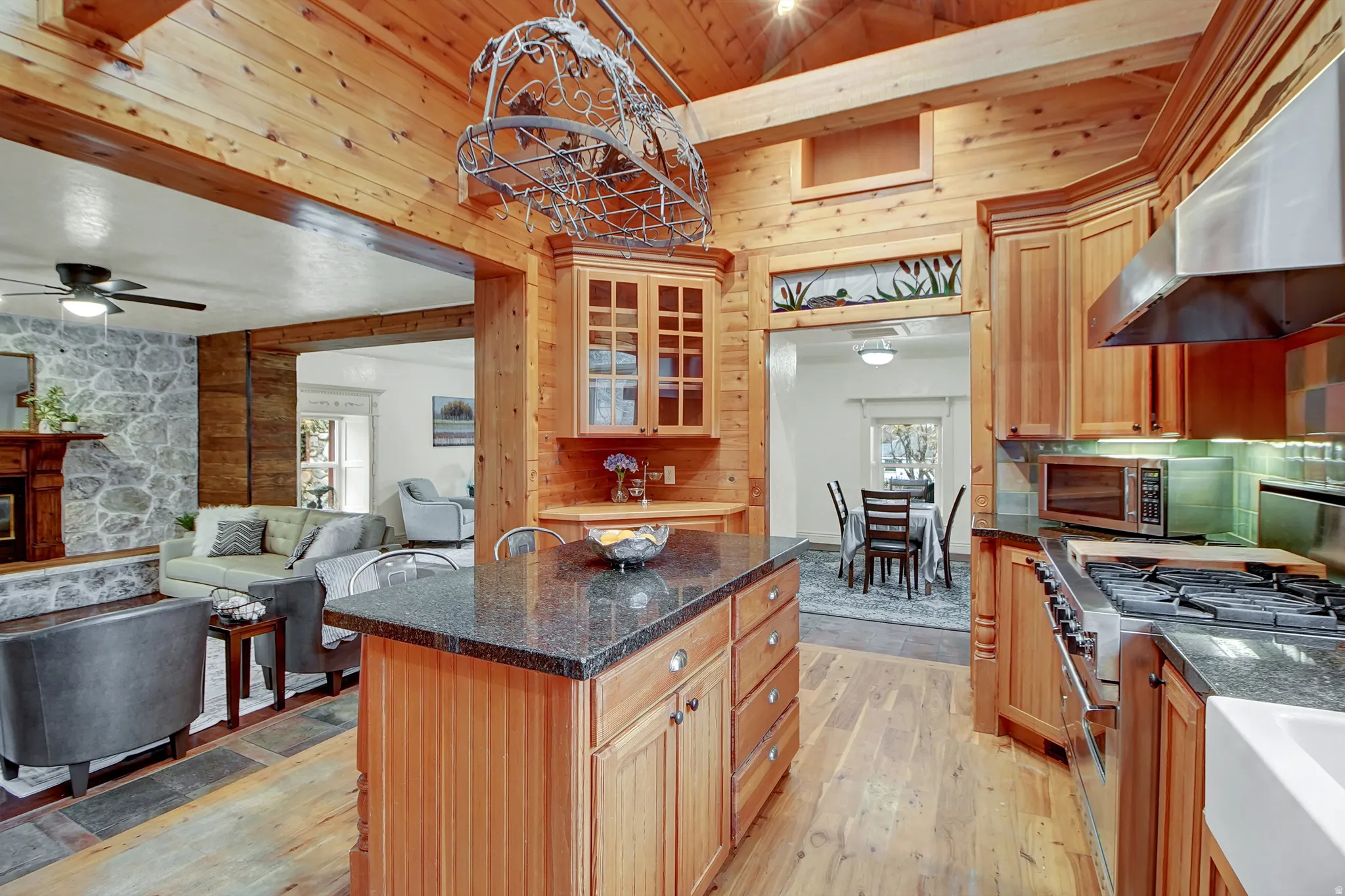 Kitchen with dark stone countertops, extractor fan, a center island, glass insert cabinets, and stainless steel appliances