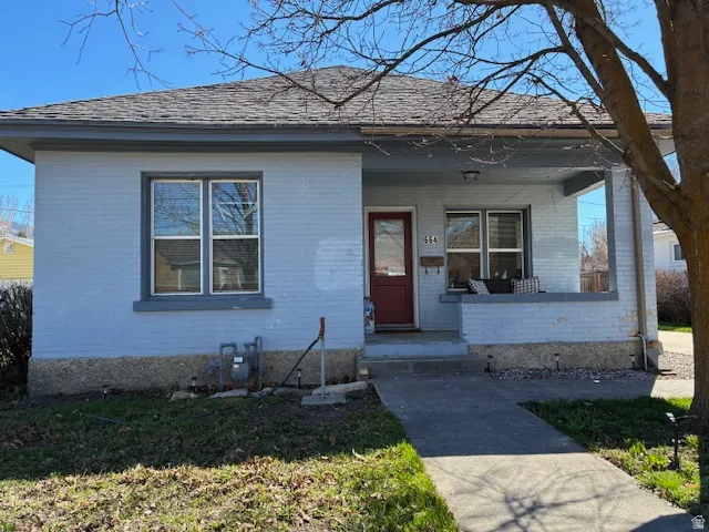 Bungalow featuring covered porch, brick siding, and a front lawn