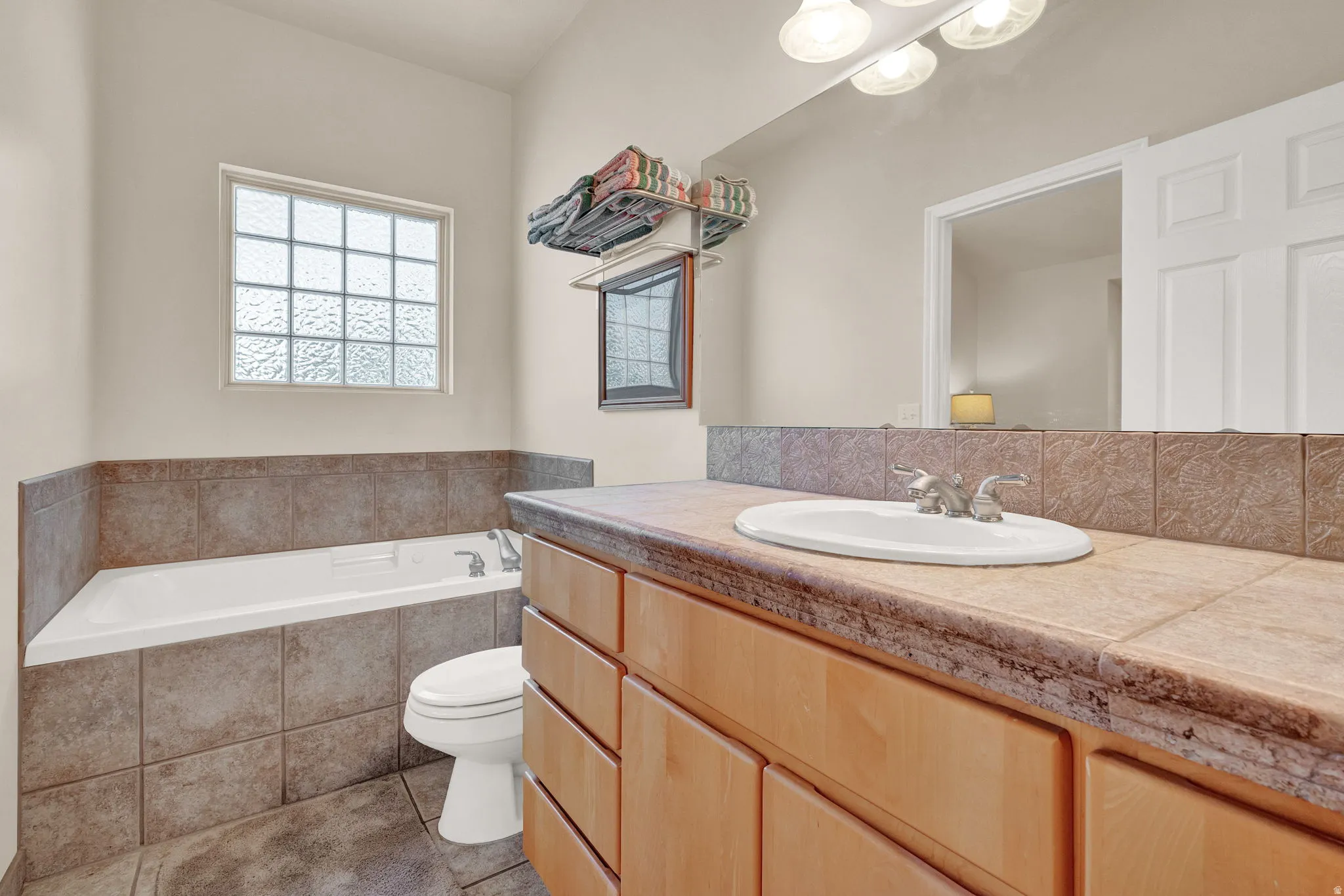 Full bath with a garden tub, vanity, and light tile patterned floors