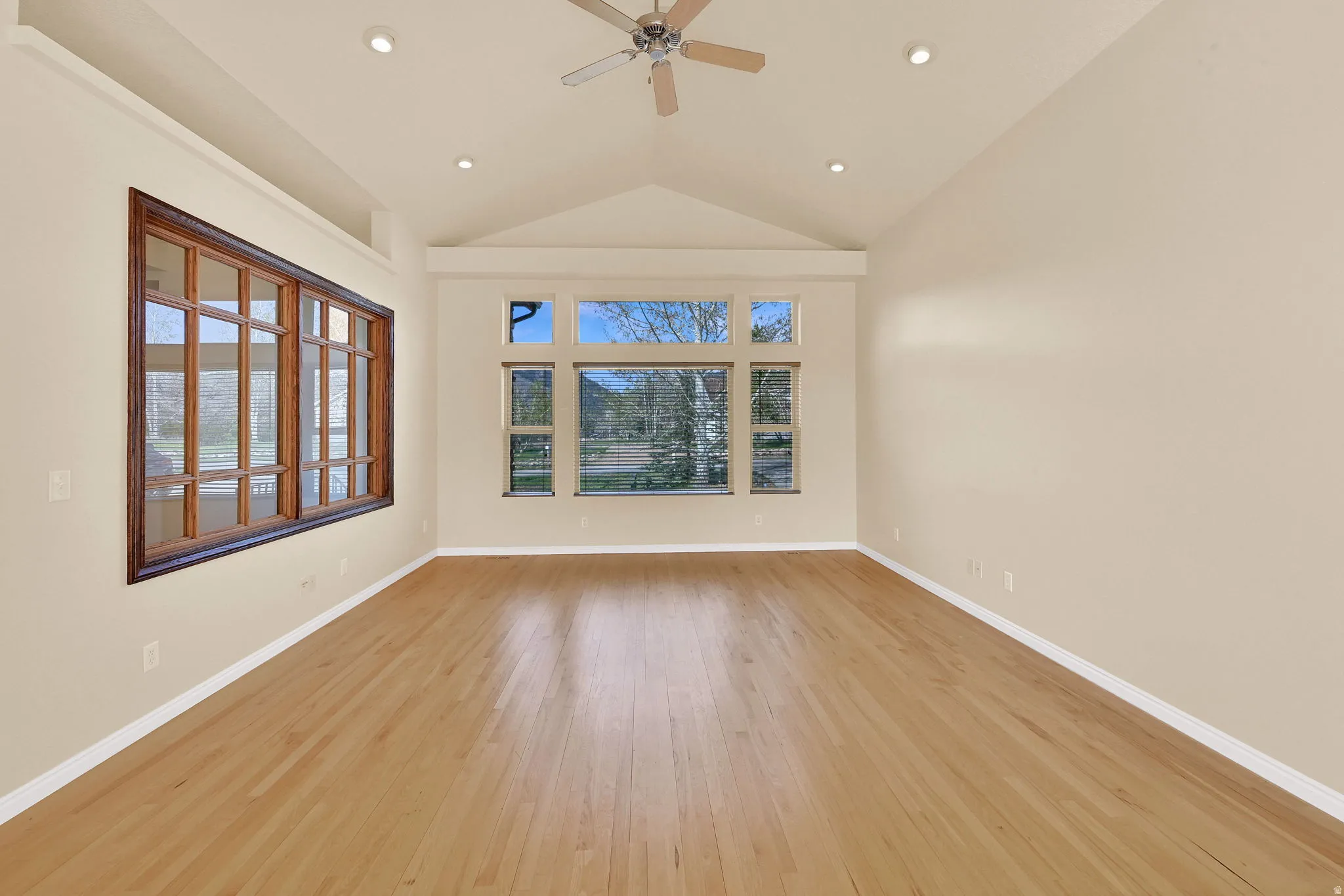 Empty room featuring ceiling fan, light wood-style floors, lofted ceiling, and recessed lighting
