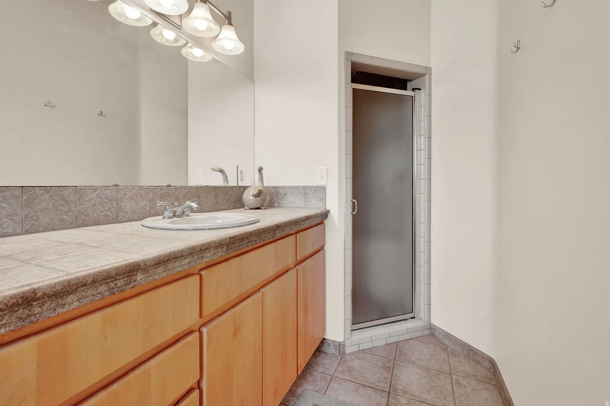 Bathroom featuring vanity, a stall shower, and light tile patterned floors