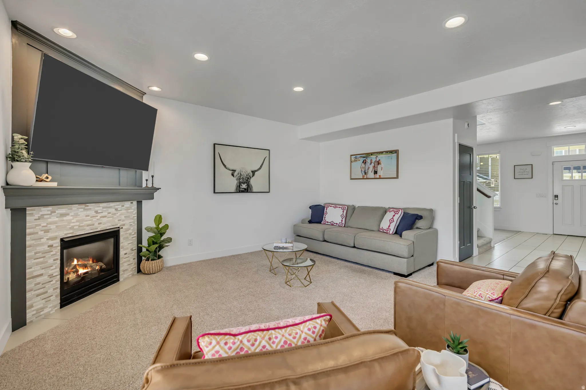 Living room with recessed lighting, a stone fireplace, and light carpet