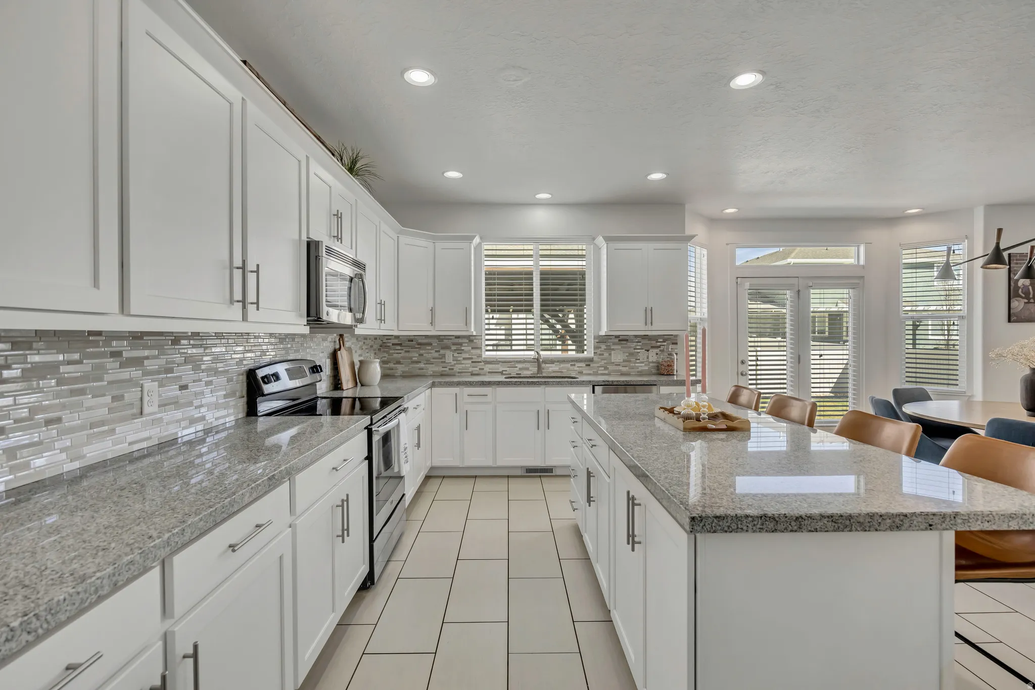 Kitchen featuring a breakfast bar area, stainless steel appliances, a center island, white cabinetry, and light stone counters
