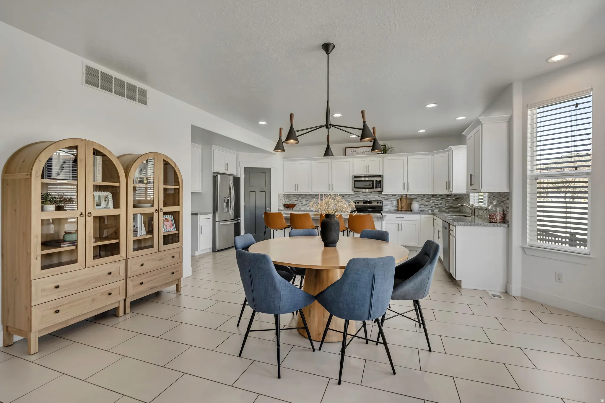 Dining room with light tile patterned flooring, recessed lighting, and a textured ceiling