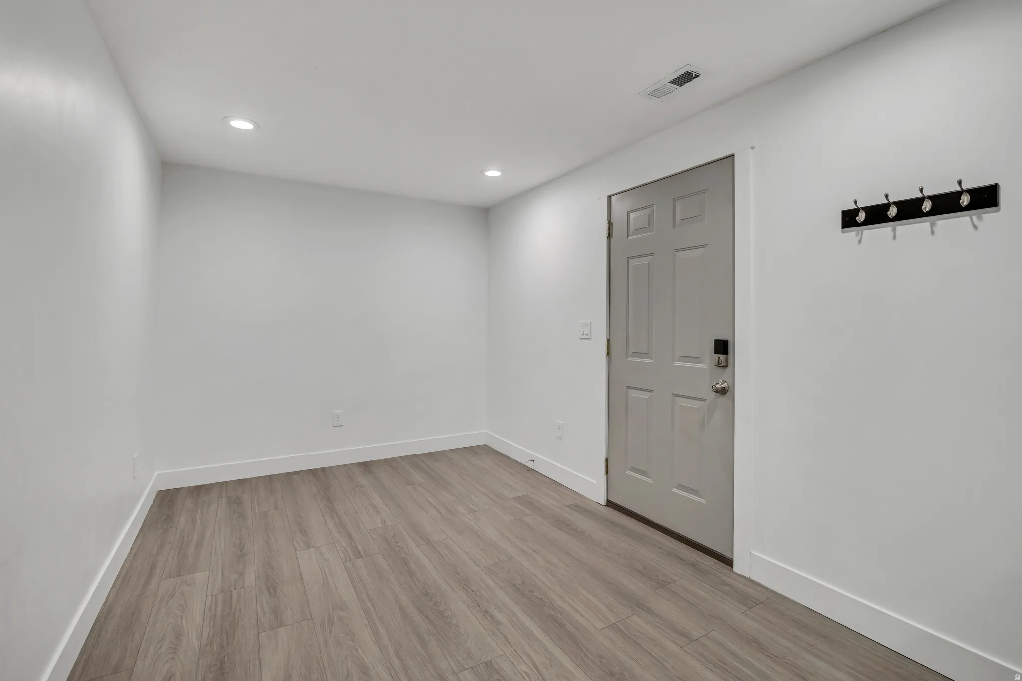 Empty room with light wood finished floors and recessed lighting