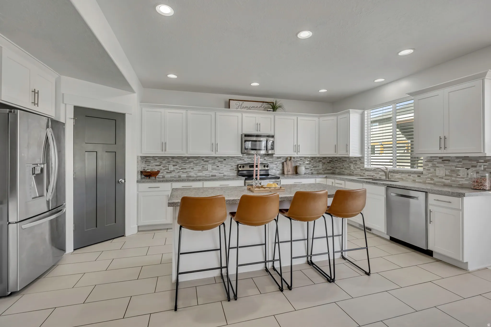 Kitchen with stainless steel appliances, white cabinets, a breakfast bar area, and recessed lighting