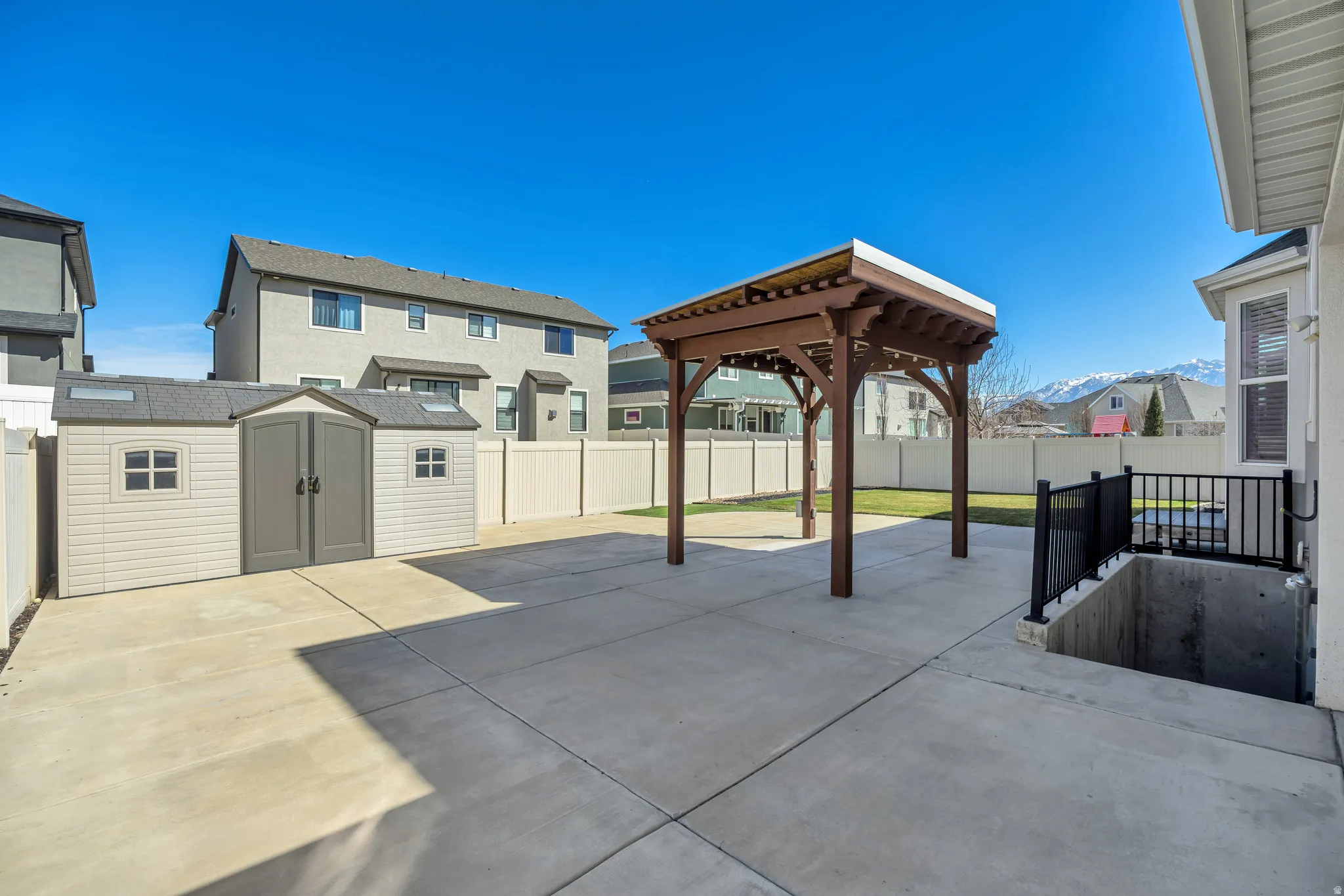 Fenced backyard featuring a patio area, a shed, a residential view, and a gazebo