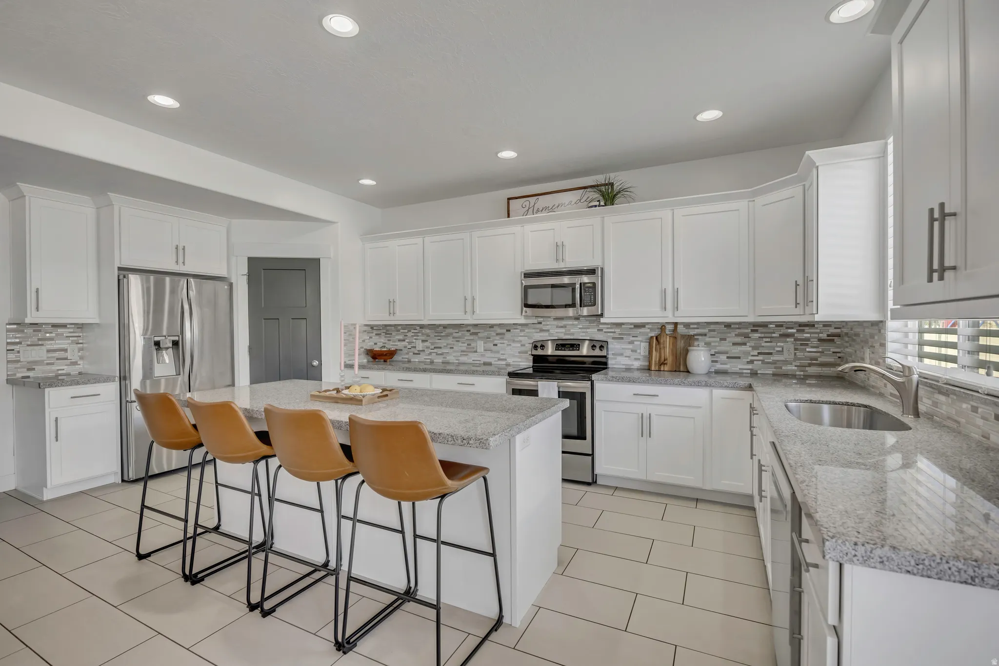 Kitchen with stainless steel appliances, white cabinetry, a center island, and recessed lighting