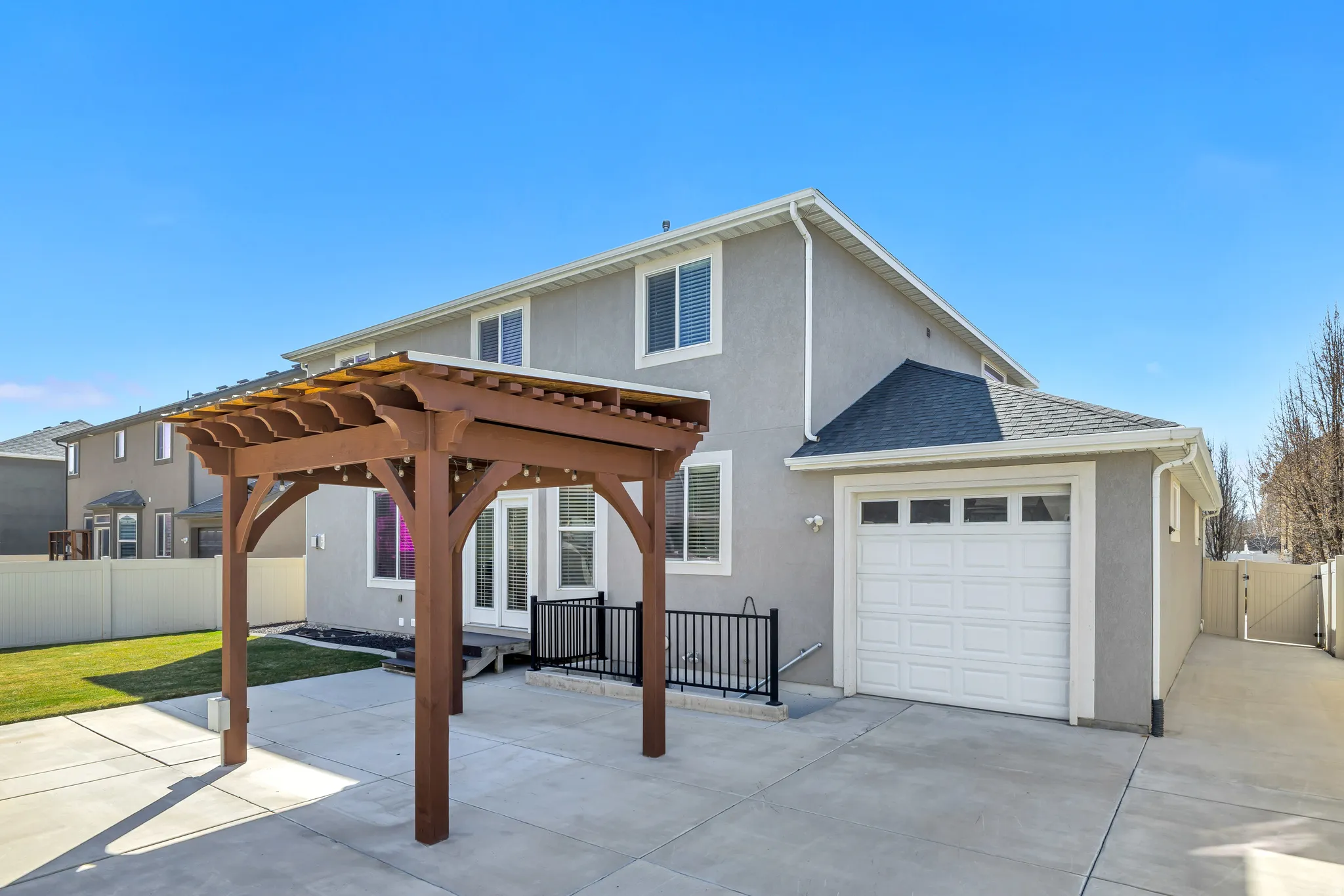 Back of property featuring a gazebo, stucco siding, a gate, a garage, and a patio
