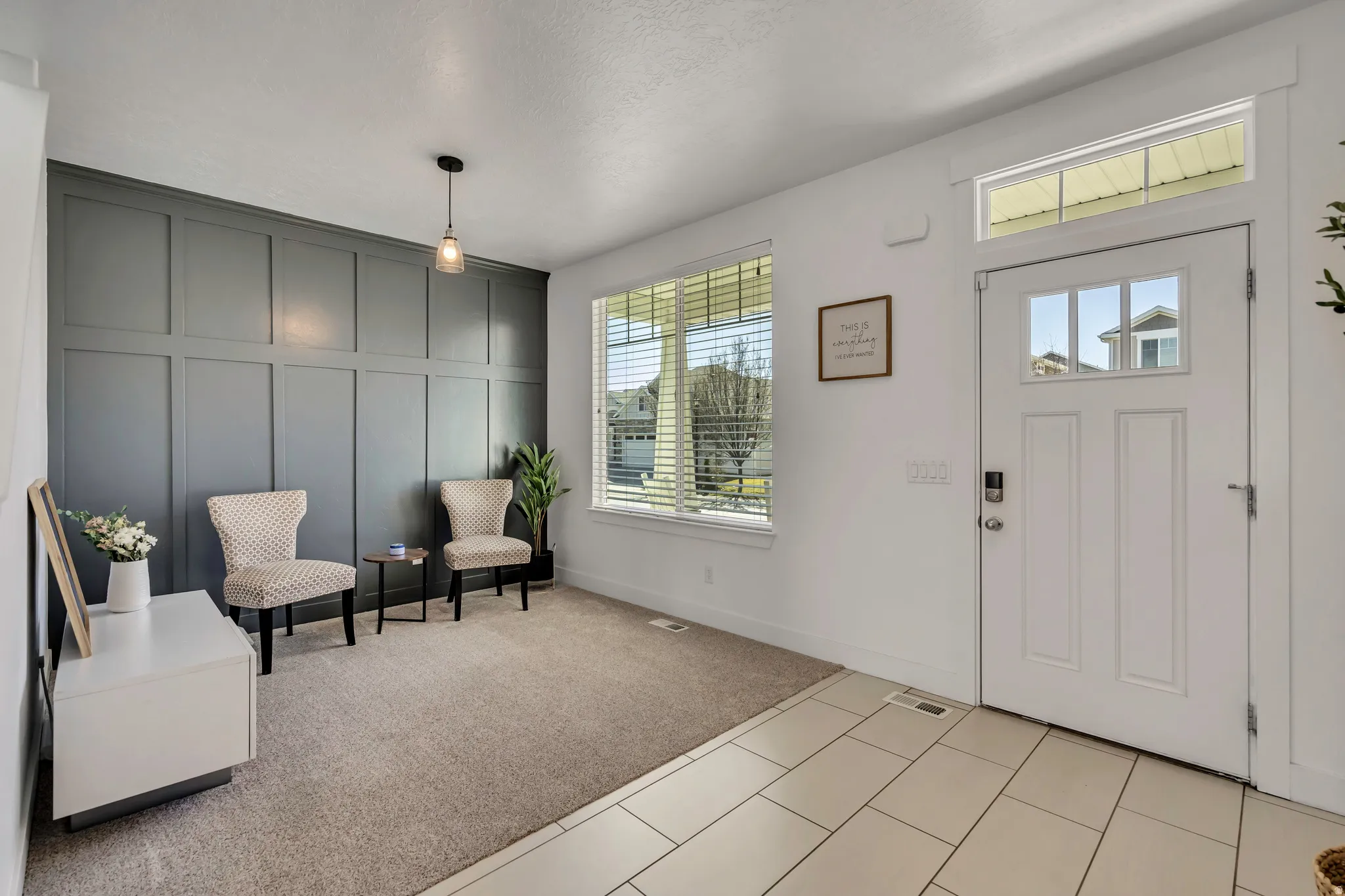 Entryway featuring a decorative wall, light carpet, and light tile patterned floors