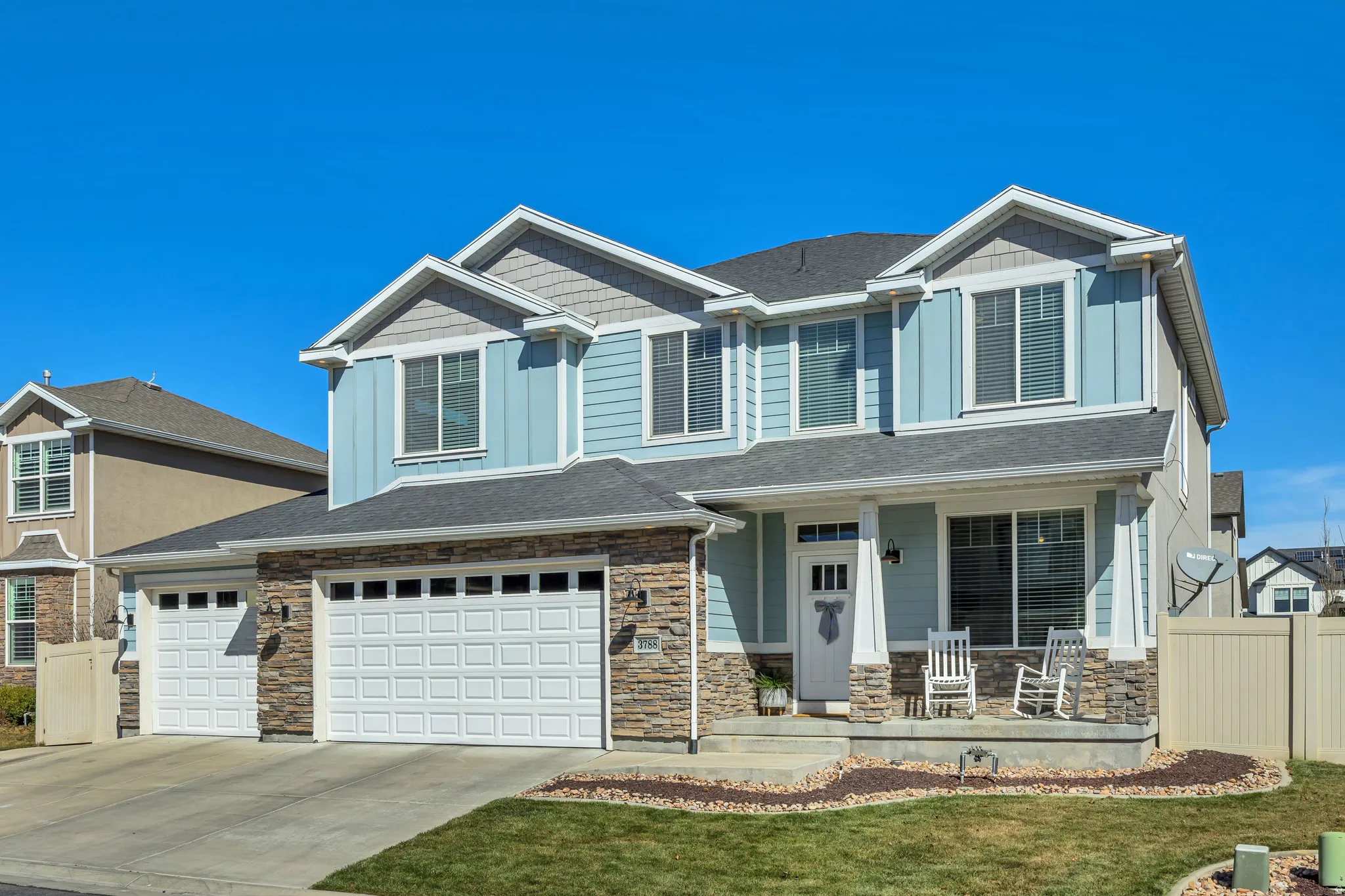 Craftsman-style house featuring board and batten siding, driveway, a porch, and stone siding