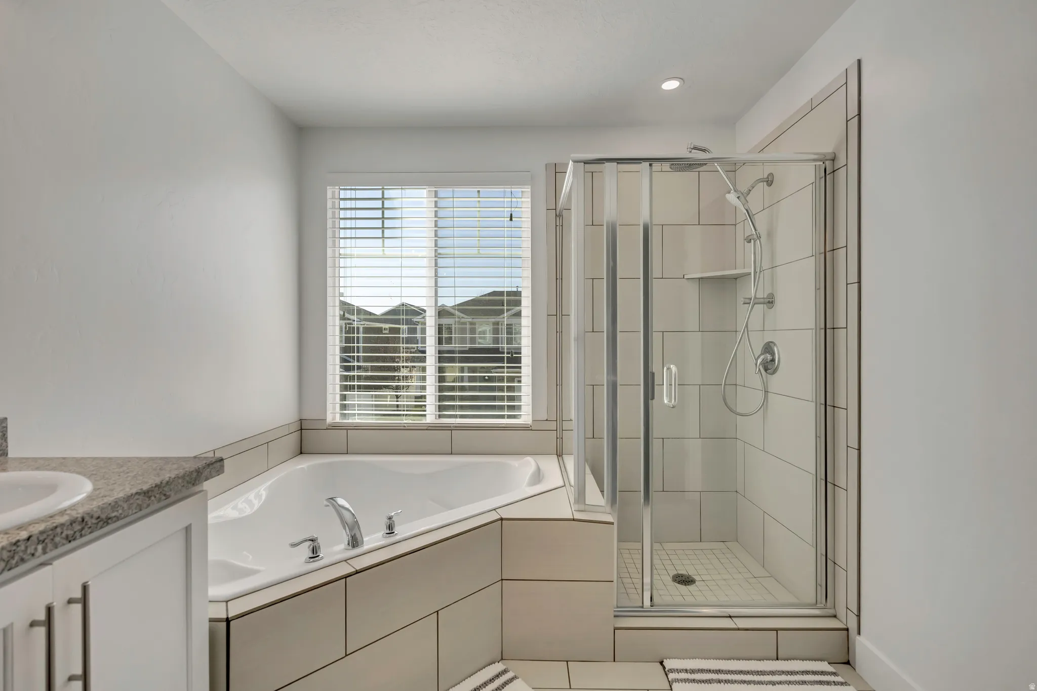 Bathroom featuring vanity, a shower stall, a bath, light tile patterned floors, and recessed lighting