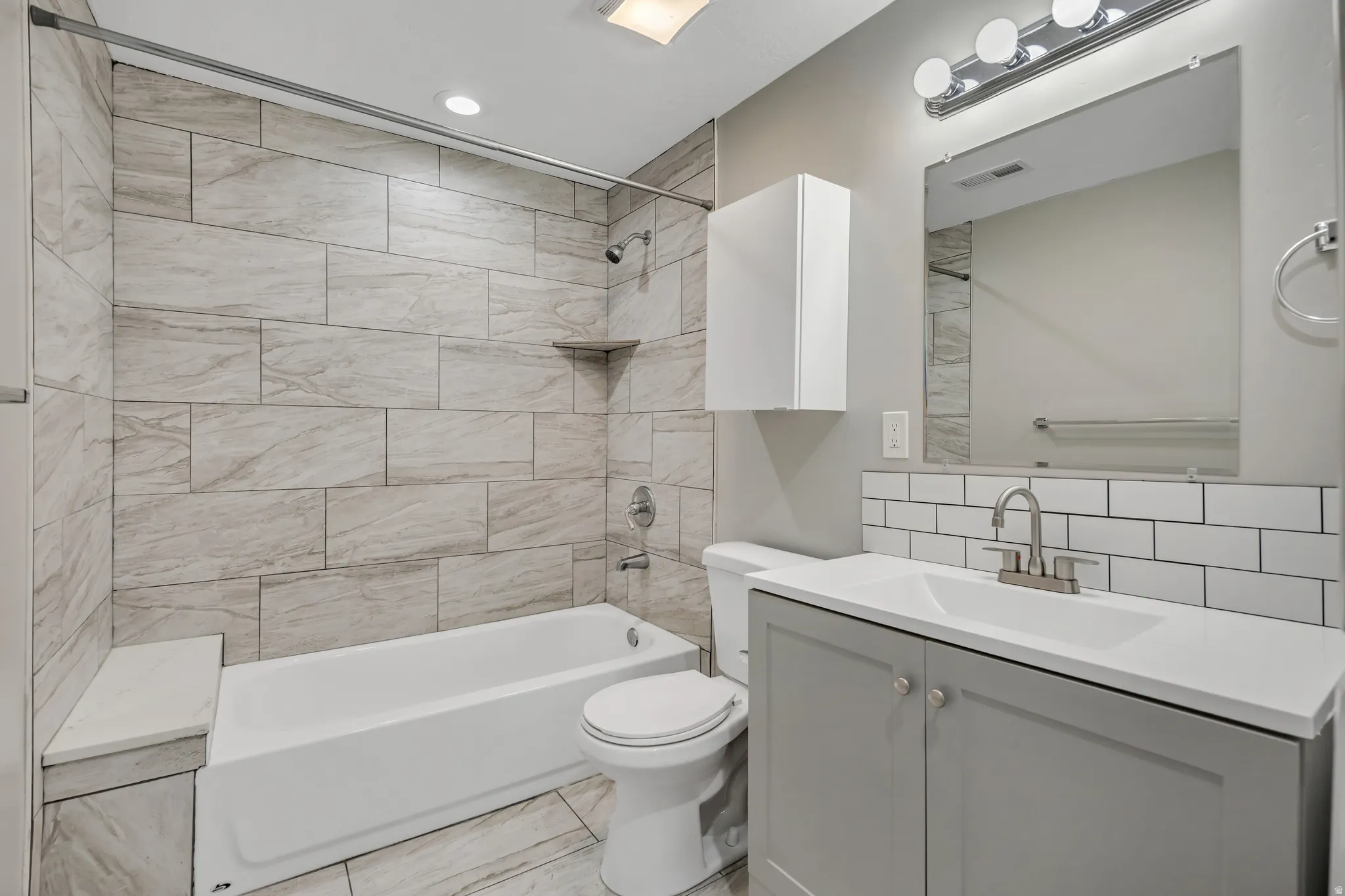 Bathroom with shower / tub combination, vanity, and tasteful backsplash