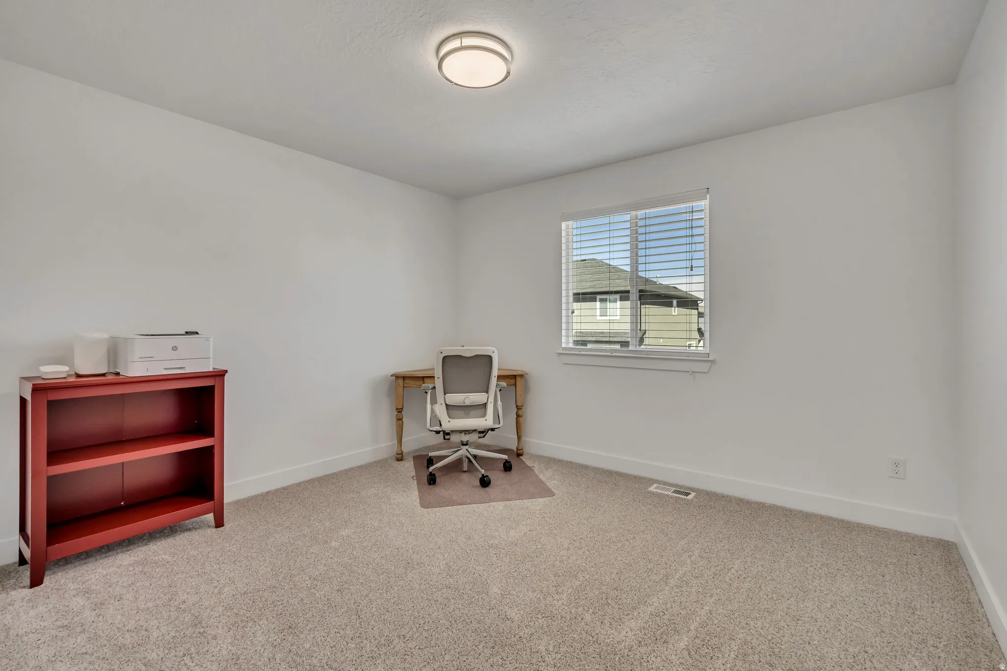 Sitting room with light colored carpet and an office area