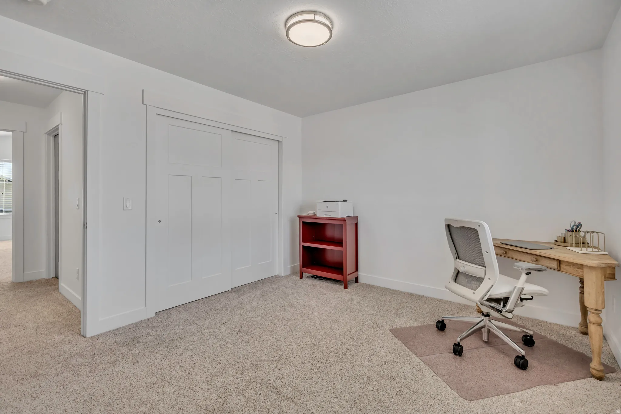 Home office with light colored carpet and baseboards
