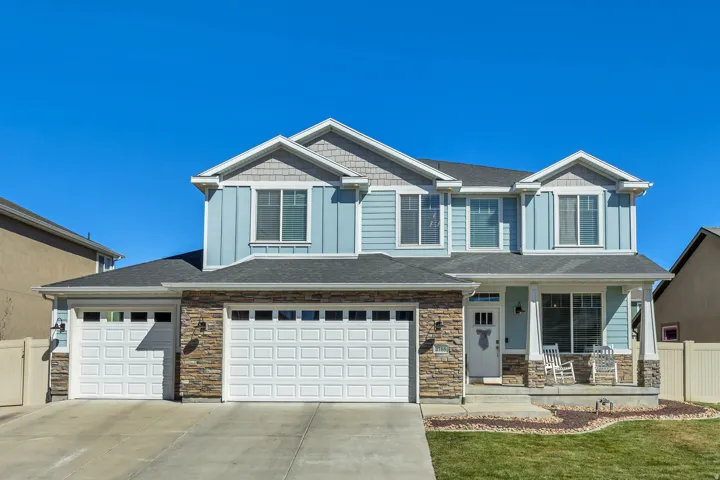 Craftsman-style house featuring board and batten siding, a porch, stone siding, and driveway