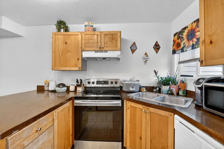 Kitchen featuring stainless steel range with electric stovetop, dark countertops, dishwasher, and a textured ceiling
