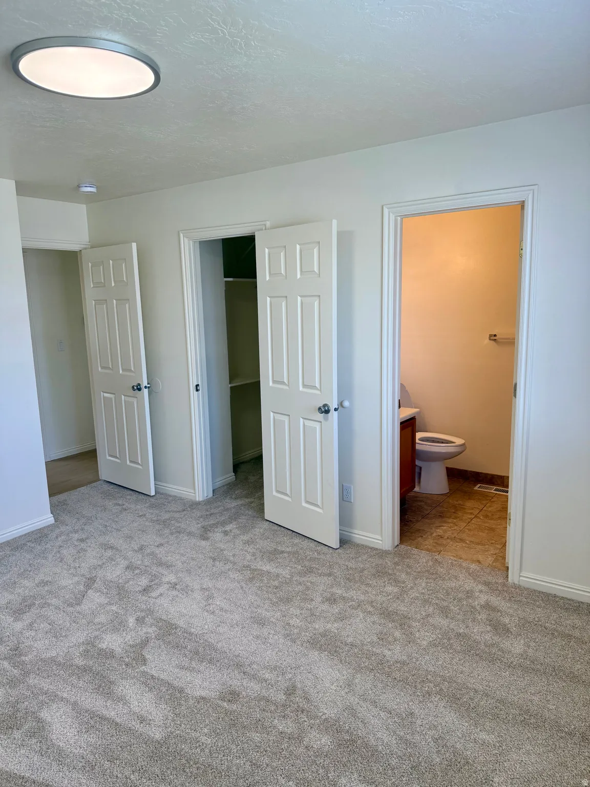 Carpeted room featuring multiple entryways, a flush-mount ceiling light, and white trim