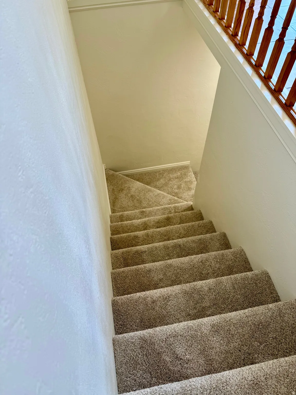 Carpeted staircase featuring a wooden spindle railing and light-toned walls