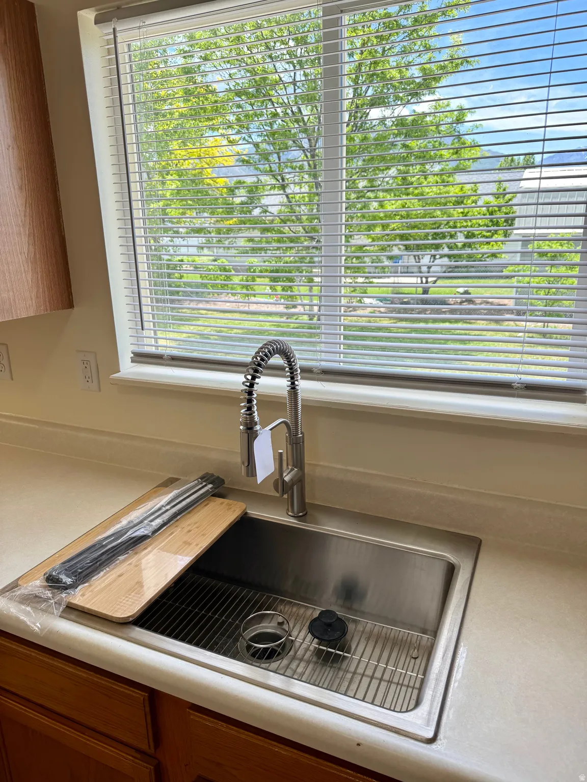 Stainless steel undermount sink featuring a gooseneck faucet with pull-down sprayer, set into a solid surface countertop