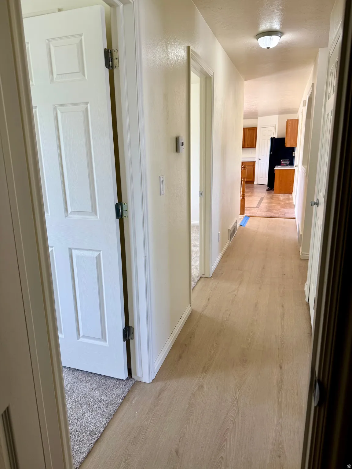 Hallway with wood-finish flooring, white paneled doors, and recessed lighting