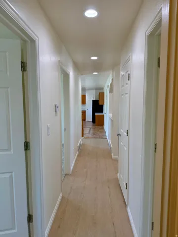 Hallway featuring recessed lighting, light wood-finish flooring, white walls, and white trim