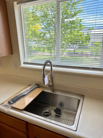 Stainless steel undermount sink featuring a gooseneck faucet with pull-down sprayer, set into a solid surface countertop