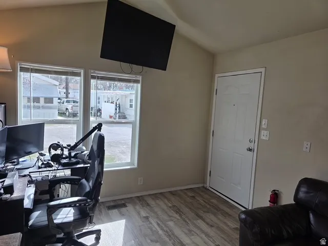 Home office with light wood finished floors and lofted ceiling