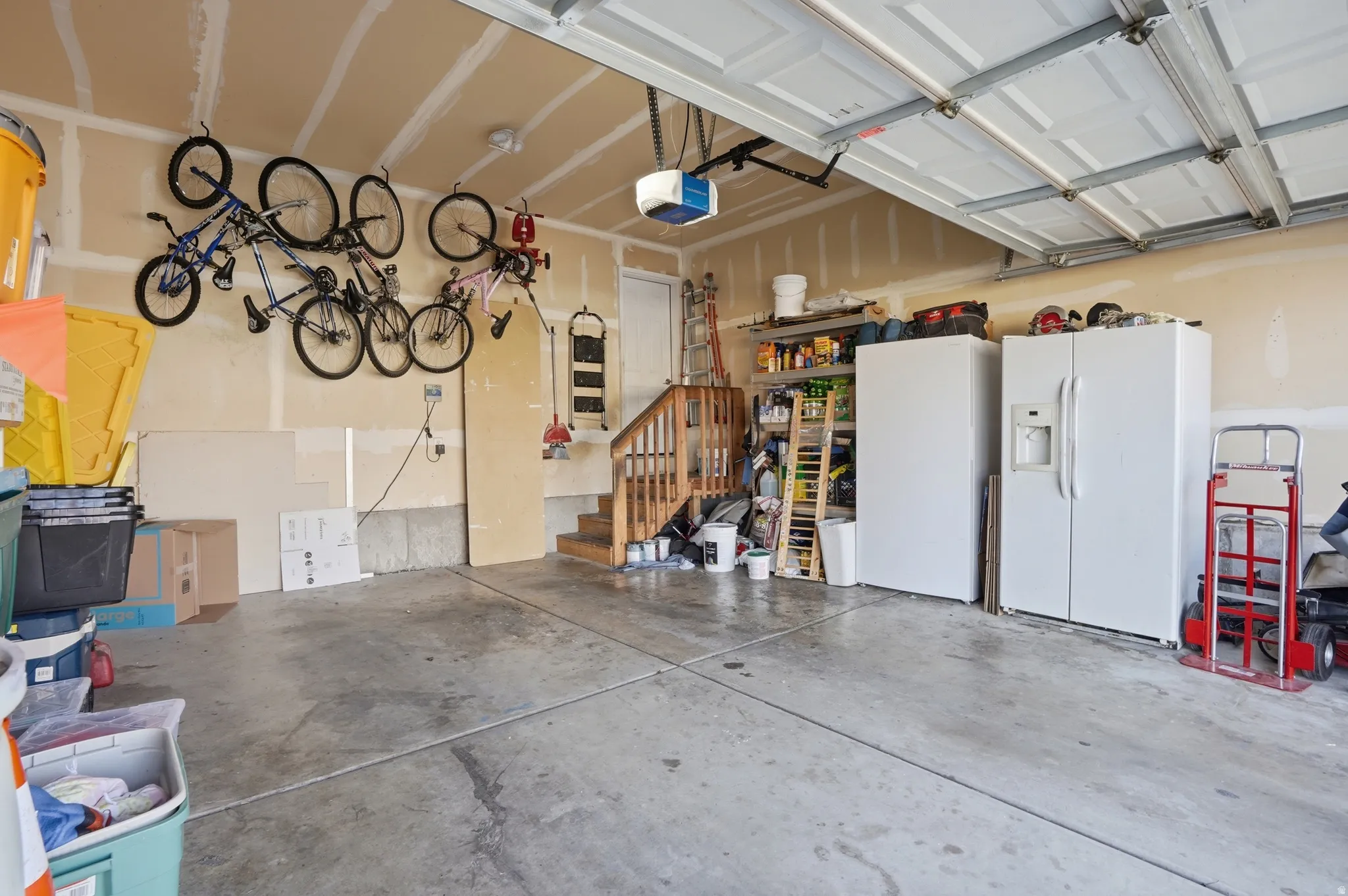Garage with white refrigerator with ice dispenser, freestanding refrigerator, and a garage door opener