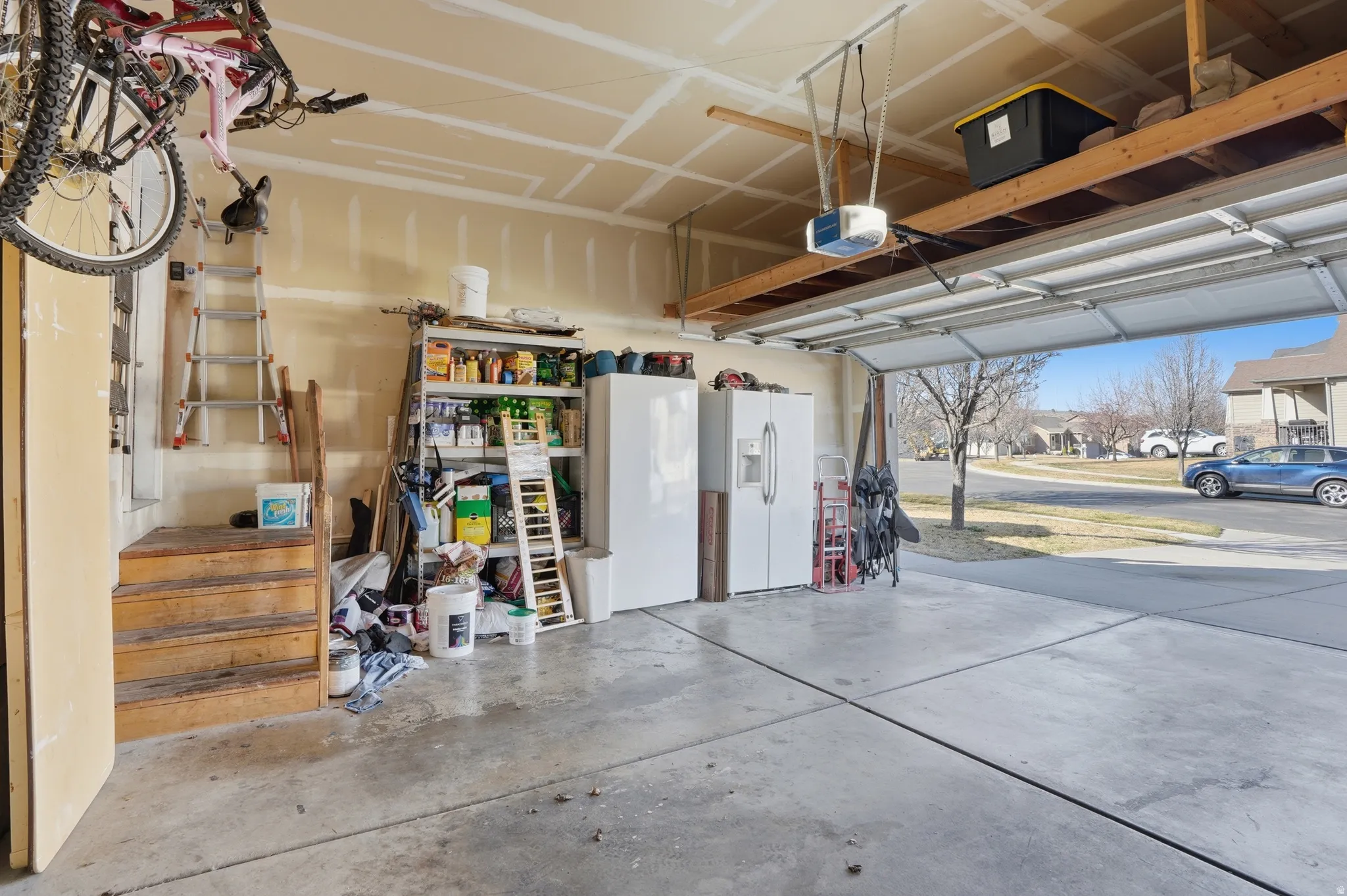 Garage featuring white refrigerator with ice dispenser, a residential view, and a garage door opener