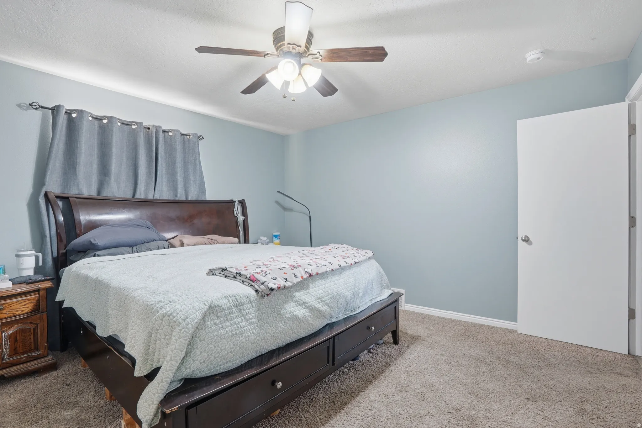 Carpeted bedroom with ceiling fan and baseboards