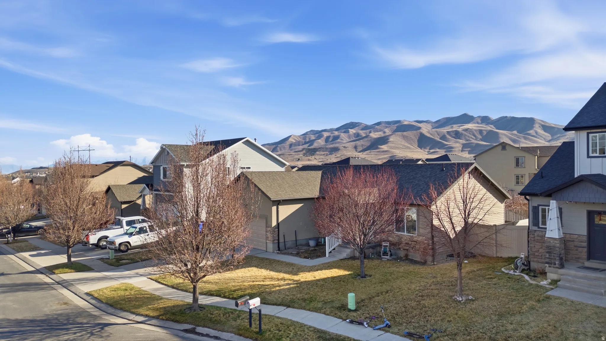 View of front facade featuring a front lawn, a mountain view, a residential view, and roof with shingles