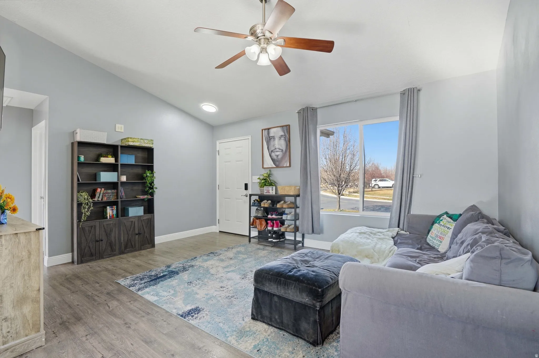 Living area with ceiling fan, vaulted ceiling, and wood finished floors